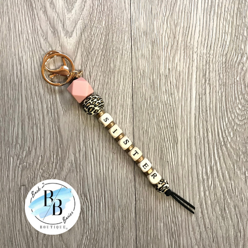 Beaded keychain with tassel. Includes leopard bead, pink, bead, and gold beads. Approximately 6 inches in length.